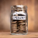 Jar labeled 'Emergency Fund' with coins and a financial checklist on a desk.